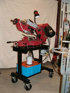 a red robot sitting on top of a blue cart in a room with white walls