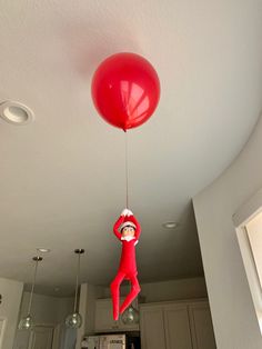 a red balloon is being suspended from the ceiling by a person wearing a santa hat