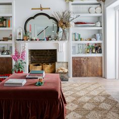 a living room filled with furniture and a fire place covered in books on top of a table