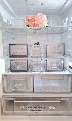 an open refrigerator filled with lots of clear plastic containers and flowers on top of it