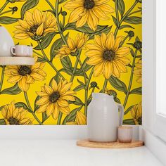 a yellow wall with sunflowers painted on it and two white vases next to each other