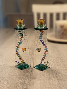 two glass candlesticks sitting on top of a wooden table