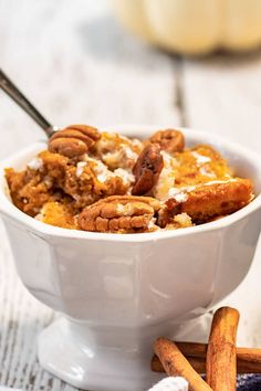 a white bowl filled with food on top of a table next to some cinnamon sticks