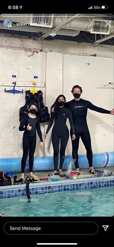 three people in wetsuits are standing on a diving board near a swimming pool