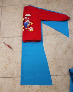 a red shirt laying on top of a tile floor next to a blue piece of cloth