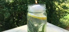 a candle that is in a jar with some water and lemon slices on the table