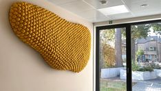 a large yellow piece of art hanging on the side of a wall next to a window