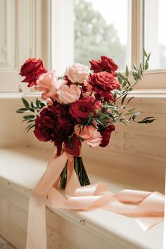 a bouquet of flowers sitting on top of a window sill next to a ribbon