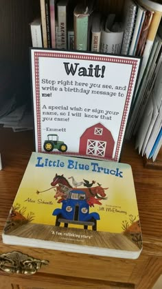 a little blue truck book sitting on top of a wooden desk next to a pile of books