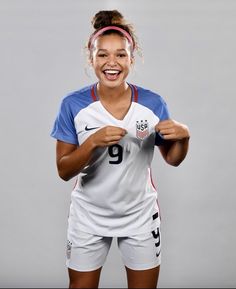 a woman in a soccer uniform is smiling and holding her hands up to her chest