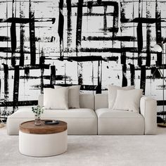 a white couch sitting in front of a wall covered in black and white paint strokes