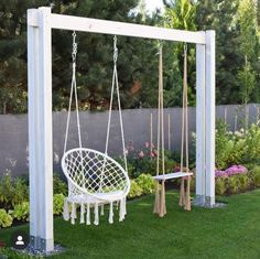 a white swing chair sitting on top of a lush green field