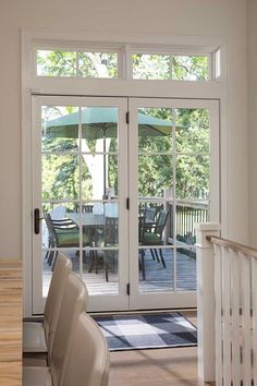 an open patio door leading to a deck with chairs and umbrellas on the porch