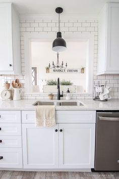 a kitchen with white cabinets and wood floors is pictured in this image, there are dishes on the dishwasher