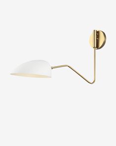 a wall light with a white shade on the side and a gold metal pole attached to it