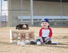 a young boy sitting on the ground next to a box with baseballs in it