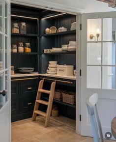 a kitchen with black cabinets and shelves filled with dishes