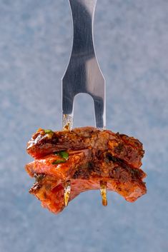 a piece of meat is being held up by a fork with a knife stuck in it