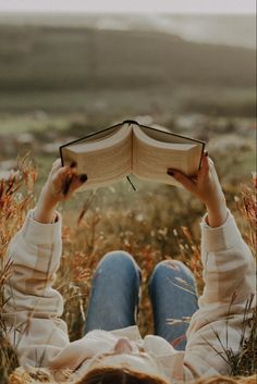 a person laying down reading a book in the middle of a field with tall grass