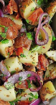 a white bowl filled with potatoes, onions and other vegetables on top of a wooden table