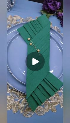 a table setting with green napkins and silverware on top of a blue plate