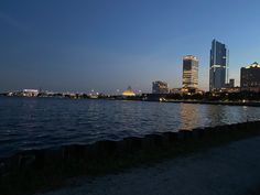 the city skyline is lit up at night by the water with skyscrapers in the background