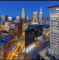 the city skyline is lit up at night with skyscrapers in the foreground and other tall buildings