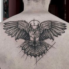 the back of a man's shoulder with an owl and cross tattoo on it