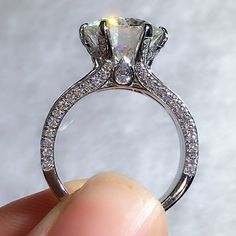 someone is holding an engagement ring with a diamond in it's center and side stones on the band