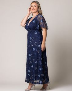 a woman wearing a blue floral print dress with sheer sleeves and an open neckline