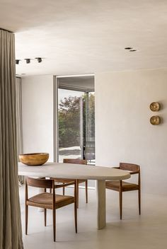 a dining room table with chairs and a bowl on top of it in front of a sliding glass door