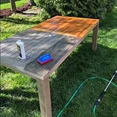 a wooden table with a sprayer on it in the grass next to a hose