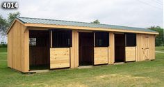 a row of wooden horse stalls in a field