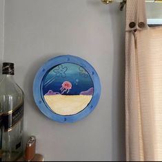 there is a blue round window with an octopus in the ocean on it and a bottle next to it