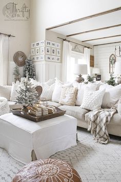 a living room filled with lots of white furniture and christmas decorations on top of it