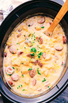 a crock pot filled with corn and sausages, garnished with parsley