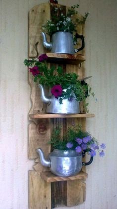 three wooden shelves with pots and pans on them, one holding flowers the other holds potted plants