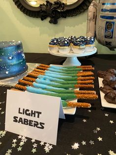 star wars themed desserts are on display at a party for light saberrs and r2d2