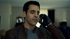 a man in a leather jacket talking on a cell phone