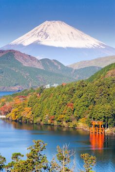 a lake surrounded by trees with a snow capped mountain in the background