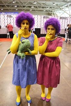 two women dressed in costumes standing next to each other with purple wigs on their heads