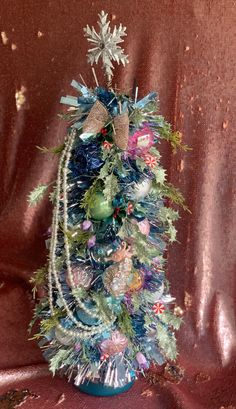 a small christmas tree with ornaments on it's top and decorations around the base