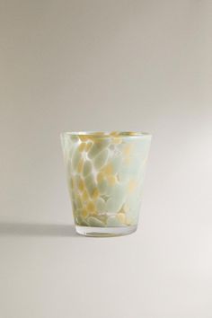 a glass cup with yellow and white designs on the inside is sitting on a table