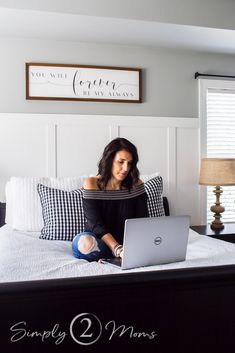 a woman sitting on top of a bed using a laptop computer