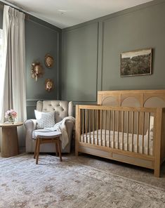 a baby's room with a crib, chair and ottoman in the corner