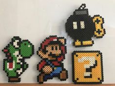 four pixel art pieces are displayed on a wall in the shape of mario bros characters