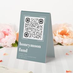 a card with a qr code on it sitting next to some flowers and papers