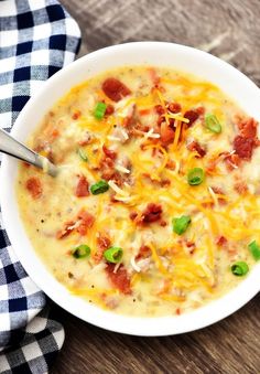 a white bowl filled with cheese and bacon soup on top of a checkered cloth