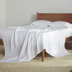 a bed with white sheets and pillows on it