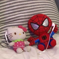 hello kitty and spiderman stuffed animals on a bed